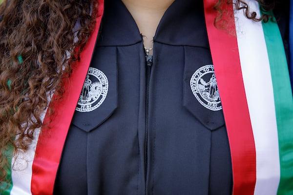 A student wears a ceremonial graduation banner with the colors of their homeland